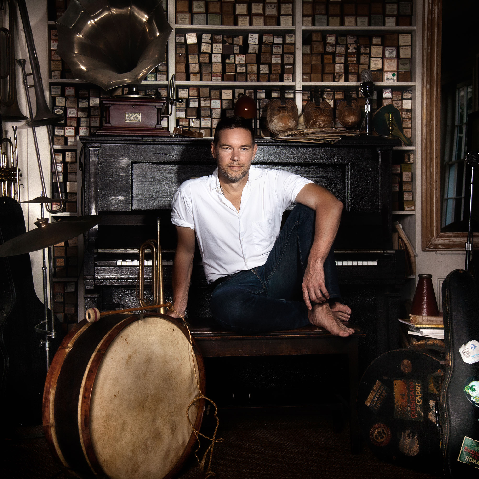 Provincetown painter John Dowd seated with his back to the keyboard of an upright piano in his home