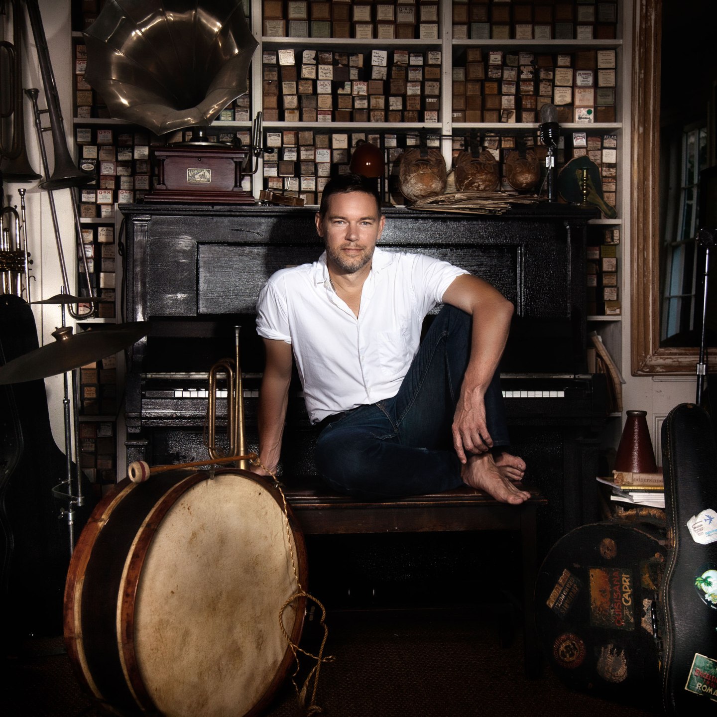 Provincetown painter John Dowd seated with his back to the keyboard of an upright piano in his home